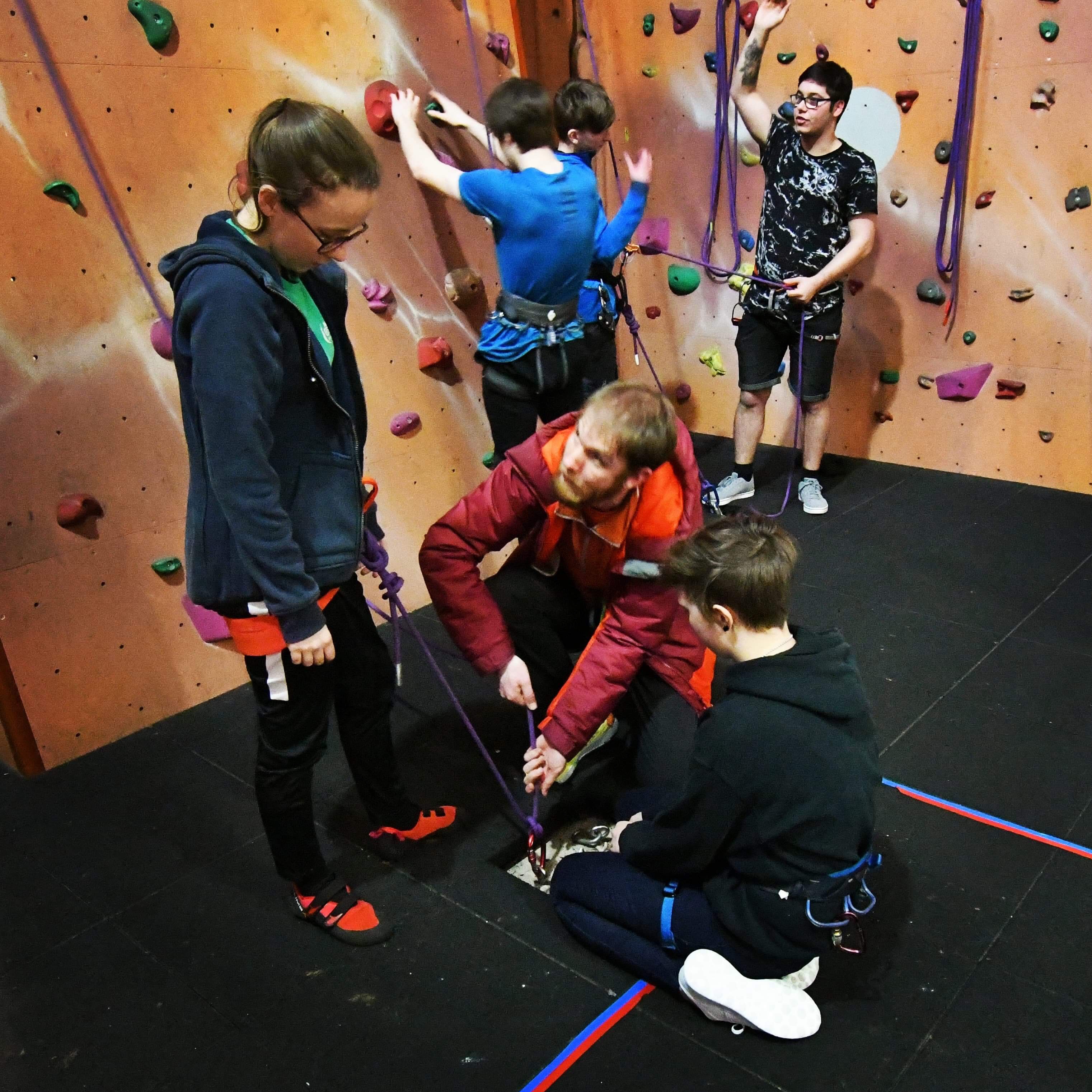 Phill in the foreground showing assistants how to adjust a clove hitch.