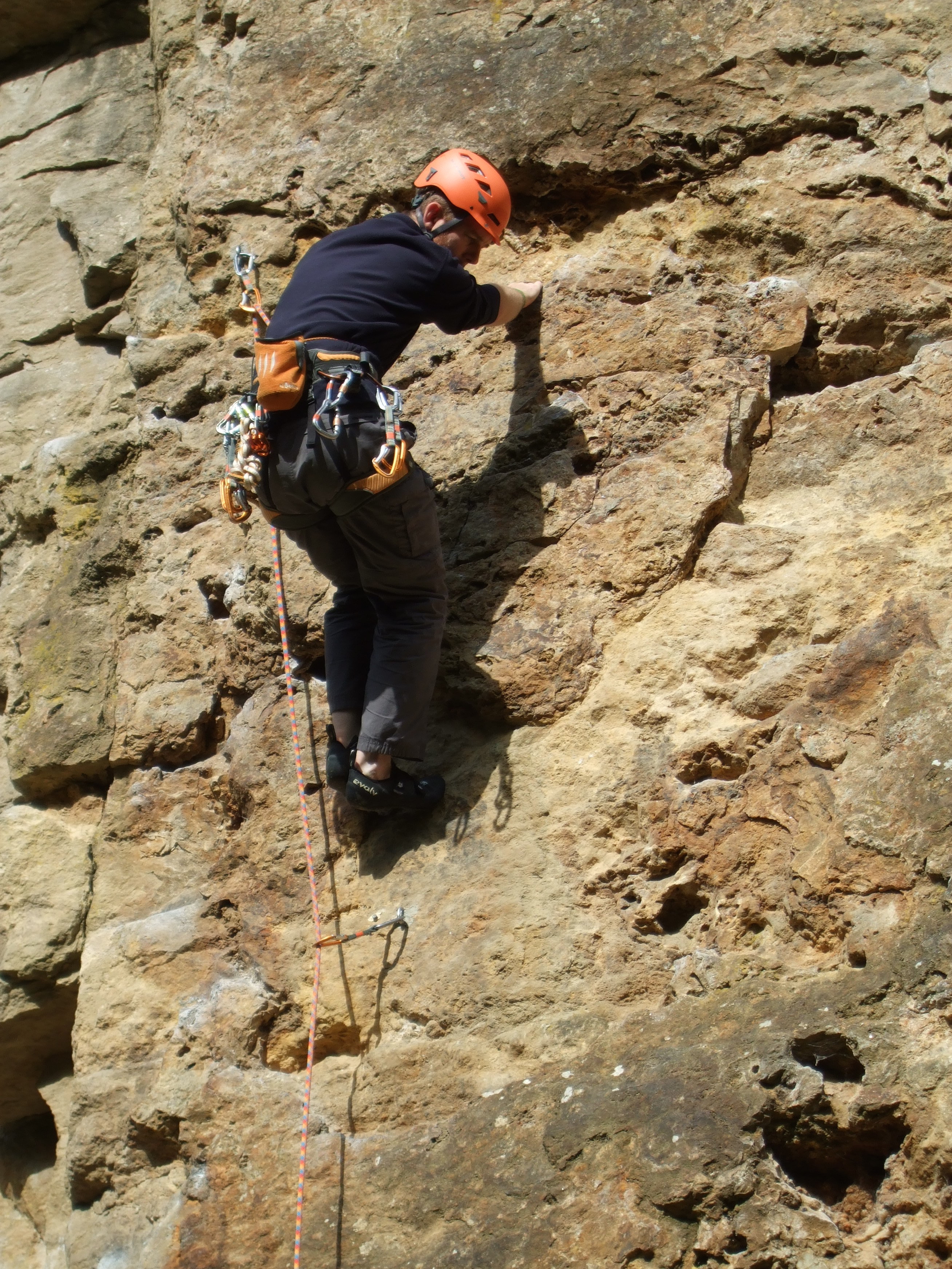 Phill climbing a yellow/brown rock, looking where to put his foot next.