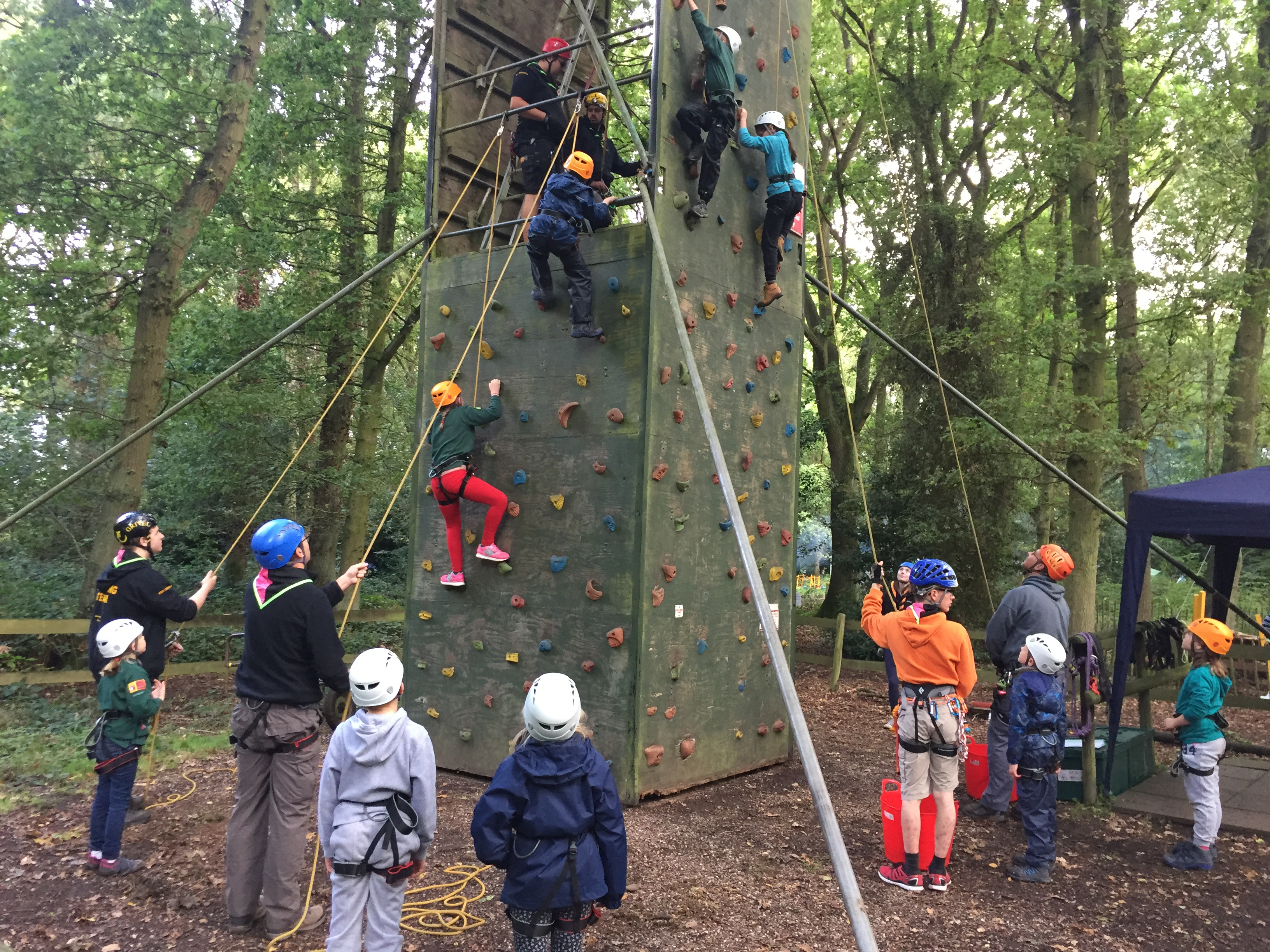 A group of scouts climbing on a boarded scaffold tower.