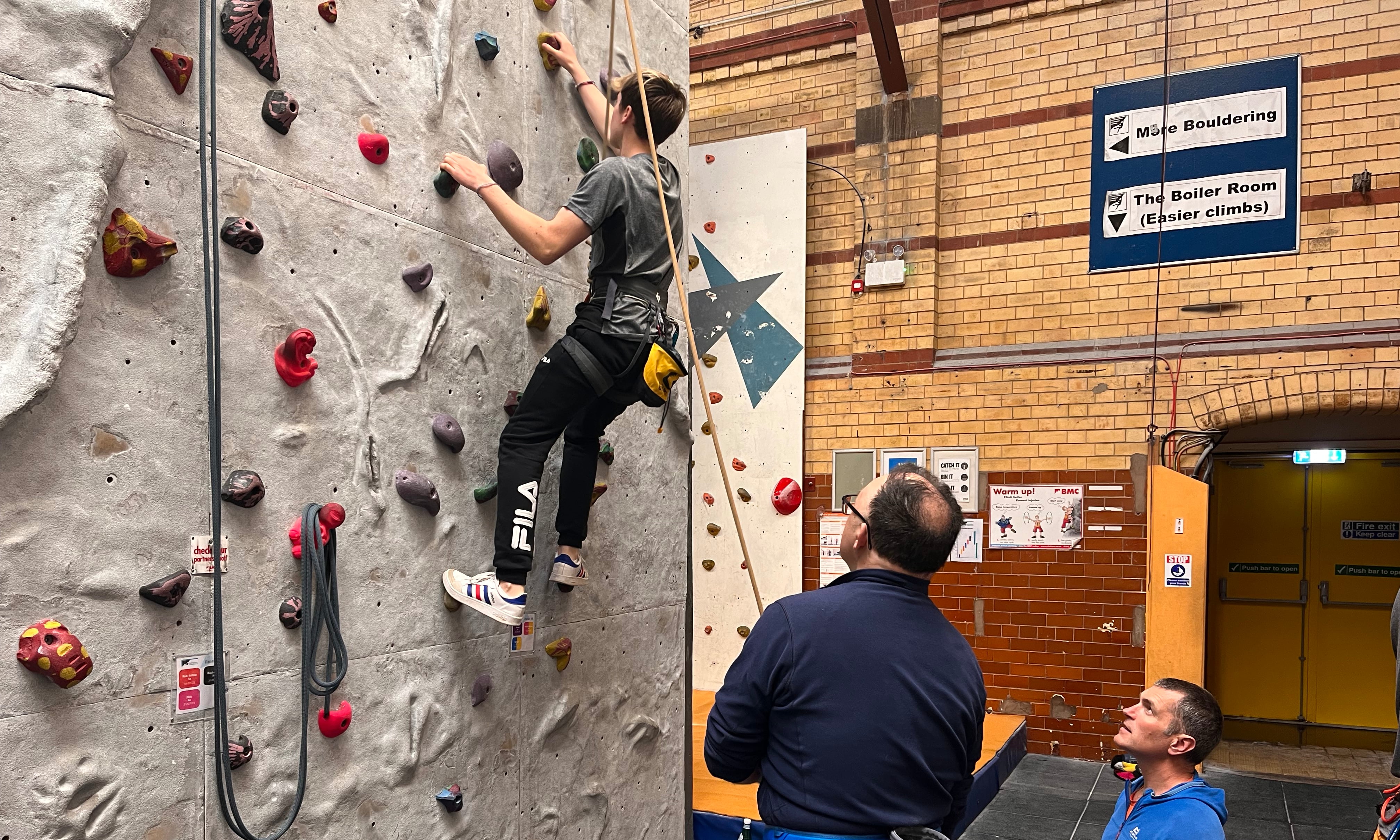 A novice belayer under supervision of an assistant.